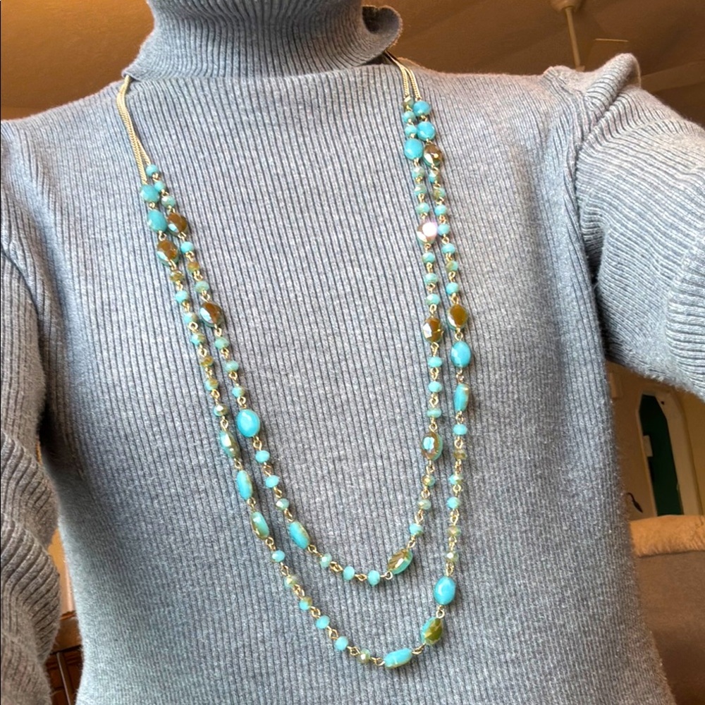 This is a beautiful long necklace-gold toned with pale blue and taupe beads.